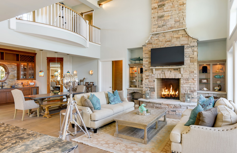 Example of a mountain style open concept medium tone wood floor living room design with blue walls, a stone fireplace and a wall-mounted tv