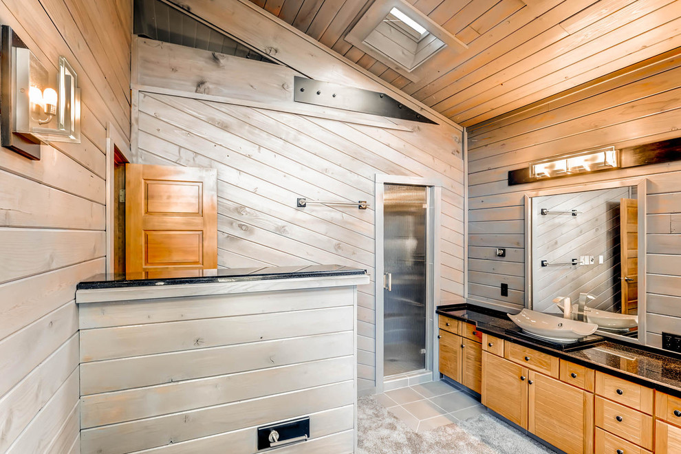 Inspiration for a mid-sized rustic master black tile and cement tile concrete floor corner shower remodel in Denver with flat-panel cabinets, light wood cabinets, a one-piece toilet, brown walls, a vessel sink and quartzite countertops