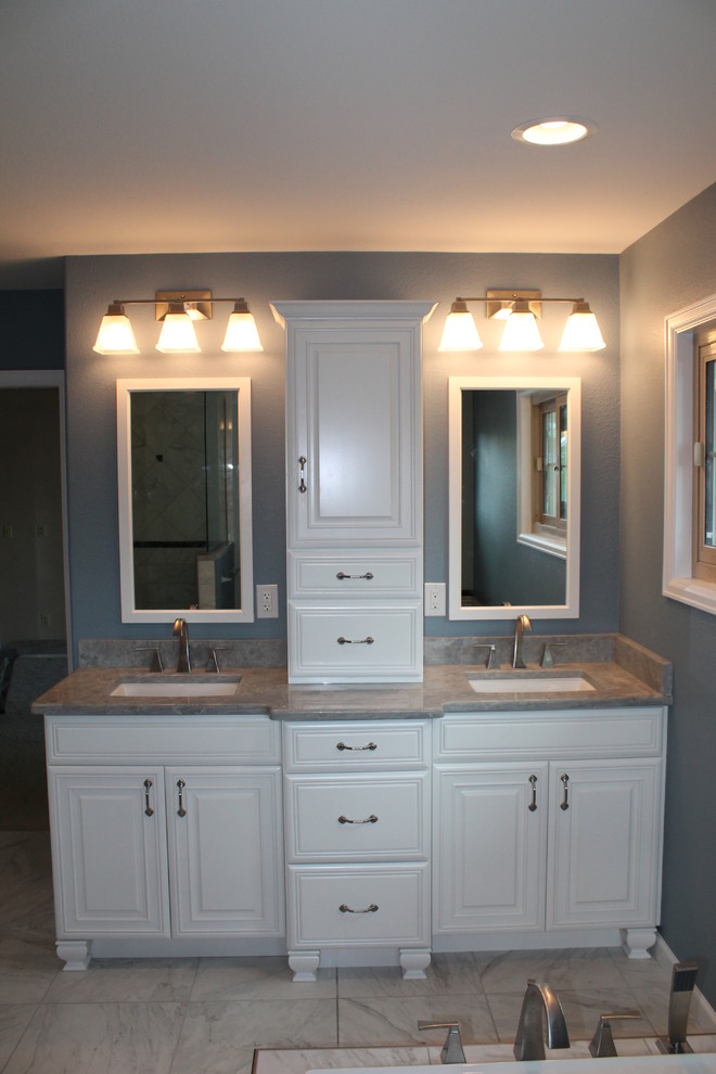 Photo of a large traditional master bathroom in Denver with an undermount sink, recessed-panel cabinets, white cabinets, granite benchtops, a drop-in tub, a double shower, a two-piece toilet, gray tile, porcelain tile, grey walls and porcelain floors.