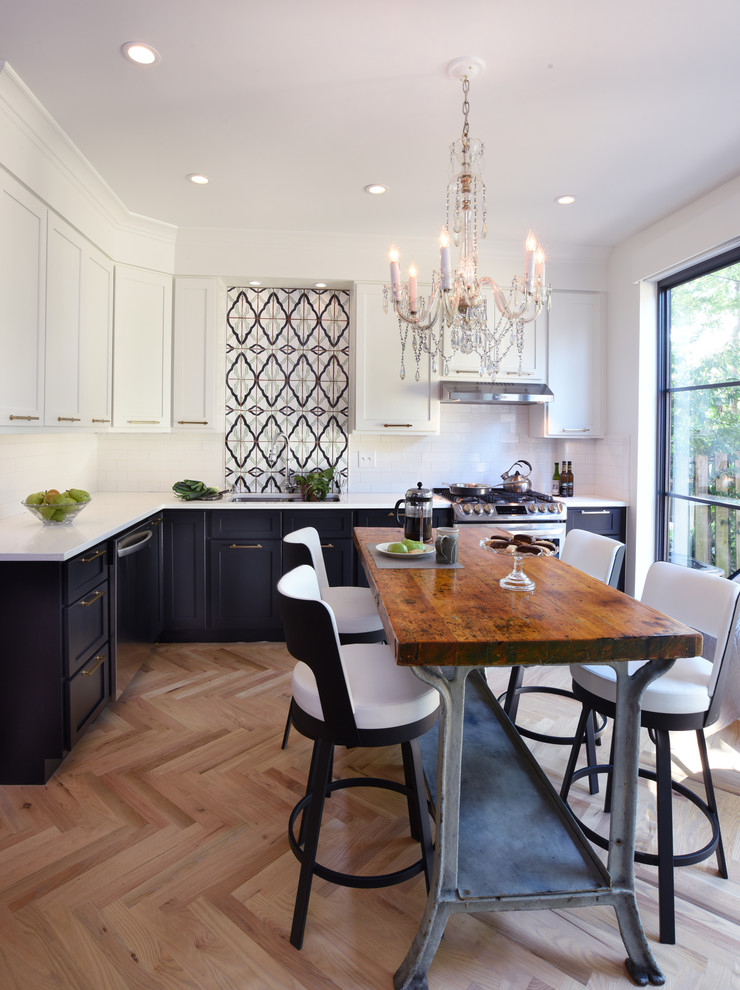Inspiration for a transitional l-shaped kitchen in Columbus with an undermount sink, shaker cabinets, black cabinets, white splashback, subway tile splashback, stainless steel appliances, light hardwood floors and with island.