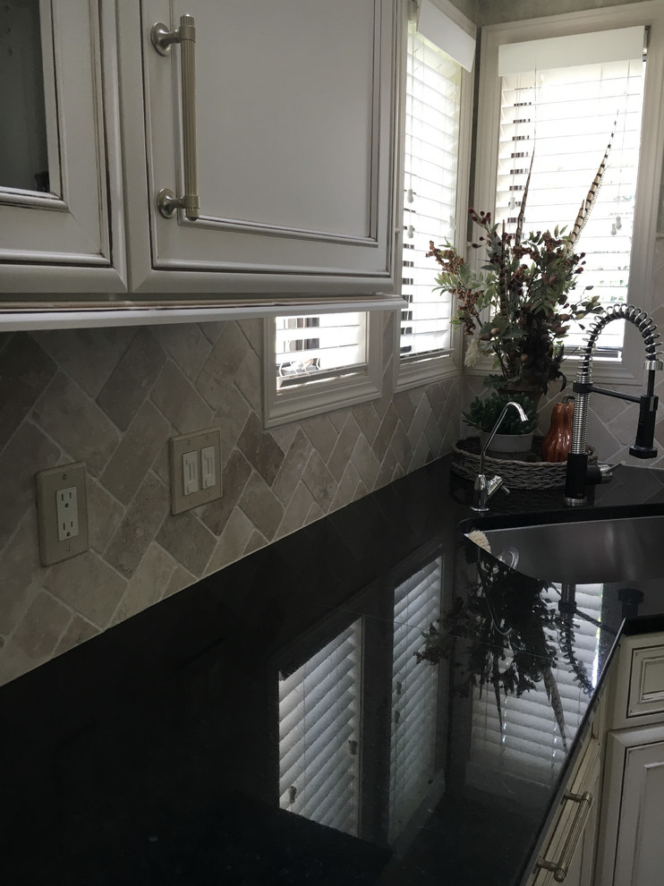 Inspiration for a large transitional u-shaped laminate floor and gray floor eat-in kitchen remodel with an undermount sink, recessed-panel cabinets, white cabinets, granite countertops, white backsplash, ceramic backsplash, stainless steel appliances, an island and black countertops