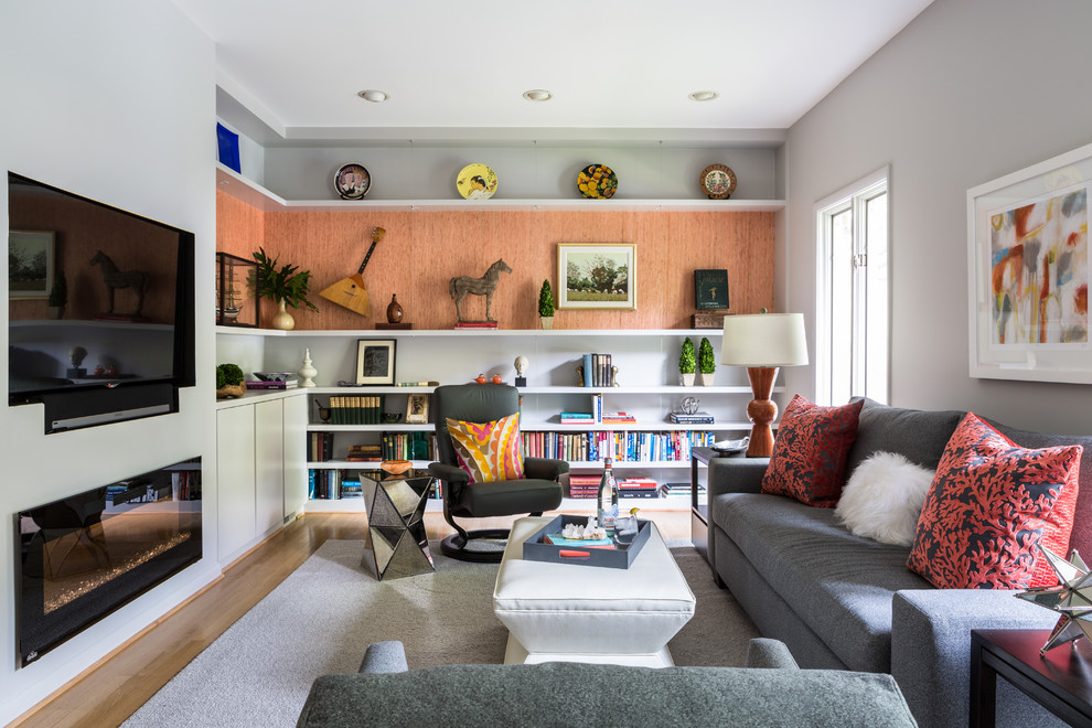 Photo of a mid-sized transitional family room in DC Metro with a library, grey walls, medium hardwood floors, a ribbon fireplace and a wall-mounted tv.