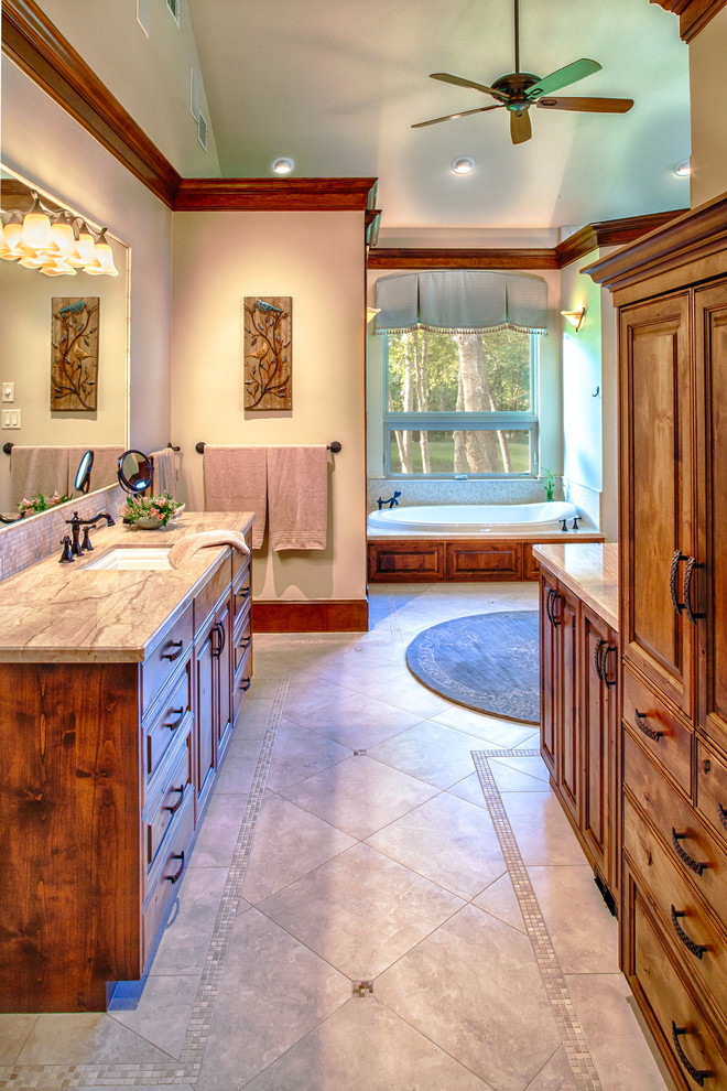 Inspiration for a large traditional master bathroom in Other with an undermount sink, raised-panel cabinets, medium wood cabinets, marble benchtops, a drop-in tub, a corner shower, a one-piece toilet, beige tile, stone tile, beige walls, travertine floors, beige floor, beige benchtops, a single vanity and a freestanding vanity.