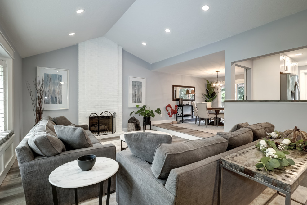 Klassisches Wohnzimmer mit grauer Wandfarbe, Vinylboden, Kamin, Kaminumrandung aus Backstein, braunem Boden und gewölbter Decke in Portland