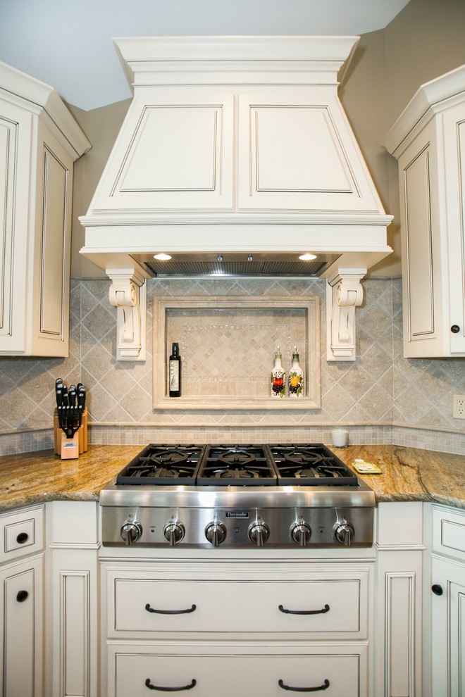 Inspiration for a large traditional kitchen in St Louis with an undermount sink, raised-panel cabinets, white cabinets, beige splashback, ceramic splashback, stainless steel appliances, dark hardwood floors and with island.