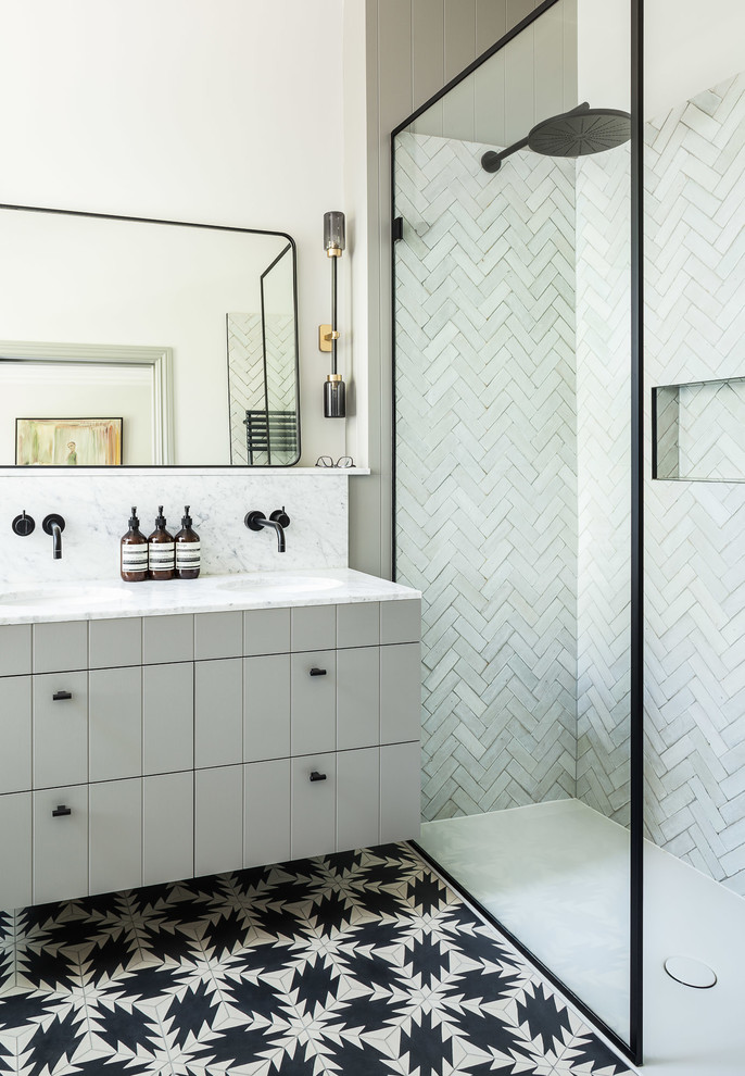 Contemporary 3/4 bathroom in London with grey cabinets, a corner shower, gray tile, white tile, beige walls, an undermount sink, multi-coloured floor and grey benchtops.