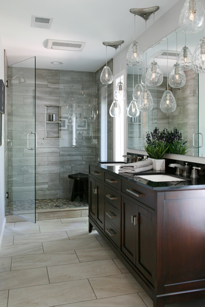 Inspiration for a transitional bathroom in Atlanta with shaker cabinets, dark wood cabinets, an alcove shower, gray tile, grey walls, an undermount sink, beige floor, a hinged shower door and black benchtops.