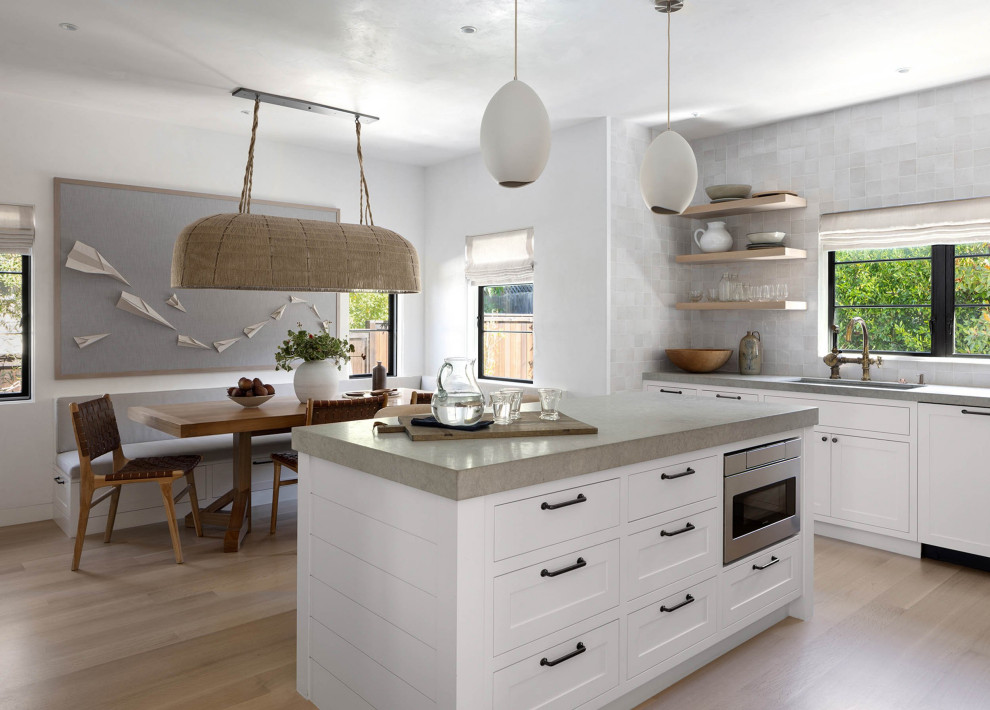 Inspiration for an expansive transitional galley open plan kitchen in San Francisco with an integrated sink, shaker cabinets, limestone benchtops, grey splashback, ceramic splashback, stainless steel appliances, light hardwood floors, with island, beige floor and grey benchtop.