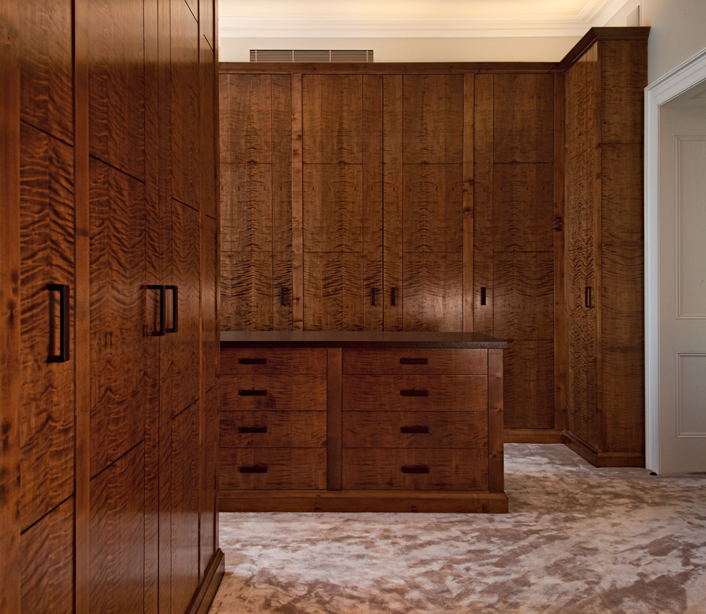 Photo of a contemporary dressing room in London with flat-panel cabinets, dark wood cabinets and carpet.