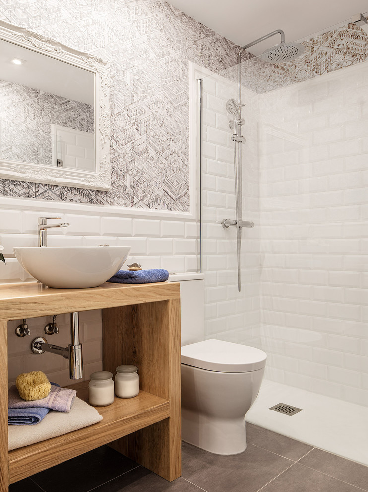 Inspiration for a small modern 3/4 bathroom in Bilbao with open cabinets, light wood cabinets, a curbless shower, a two-piece toilet, white tile, ceramic tile, white walls, ceramic floors, a vessel sink, wood benchtops, grey floor and a hinged shower door.