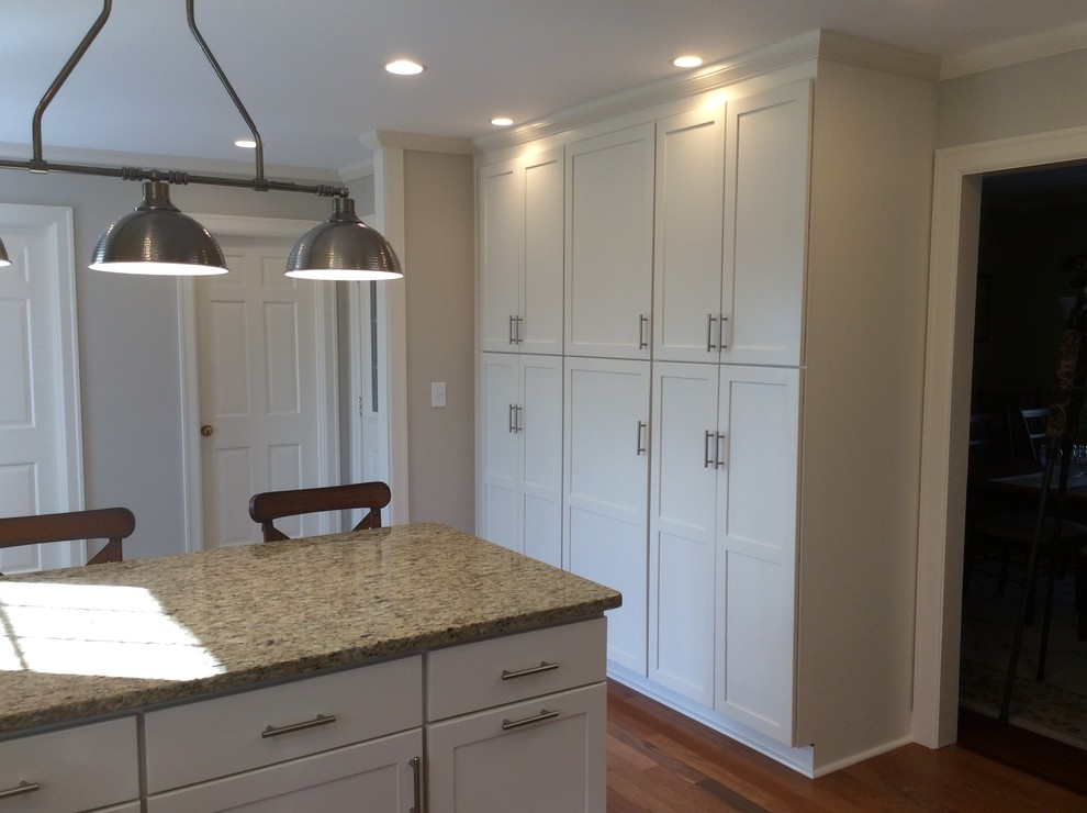 Inspiration for a transitional u-shaped medium tone wood floor kitchen remodel with an undermount sink, shaker cabinets, white cabinets, granite countertops, beige backsplash, subway tile backsplash, stainless steel appliances and a peninsula