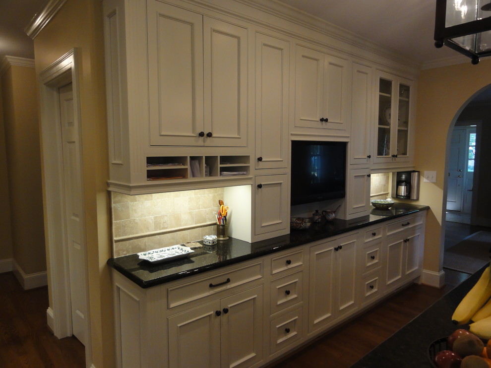This is an example of a traditional eat-in kitchen in Charlotte with an undermount sink, white cabinets, stainless steel appliances and medium hardwood floors.