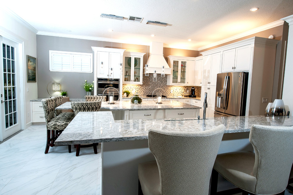 Eat-in kitchen - large transitional u-shaped porcelain tile eat-in kitchen idea in Orlando with a drop-in sink, shaker cabinets, white cabinets, quartz countertops, white backsplash, glass tile backsplash, stainless steel appliances and an island