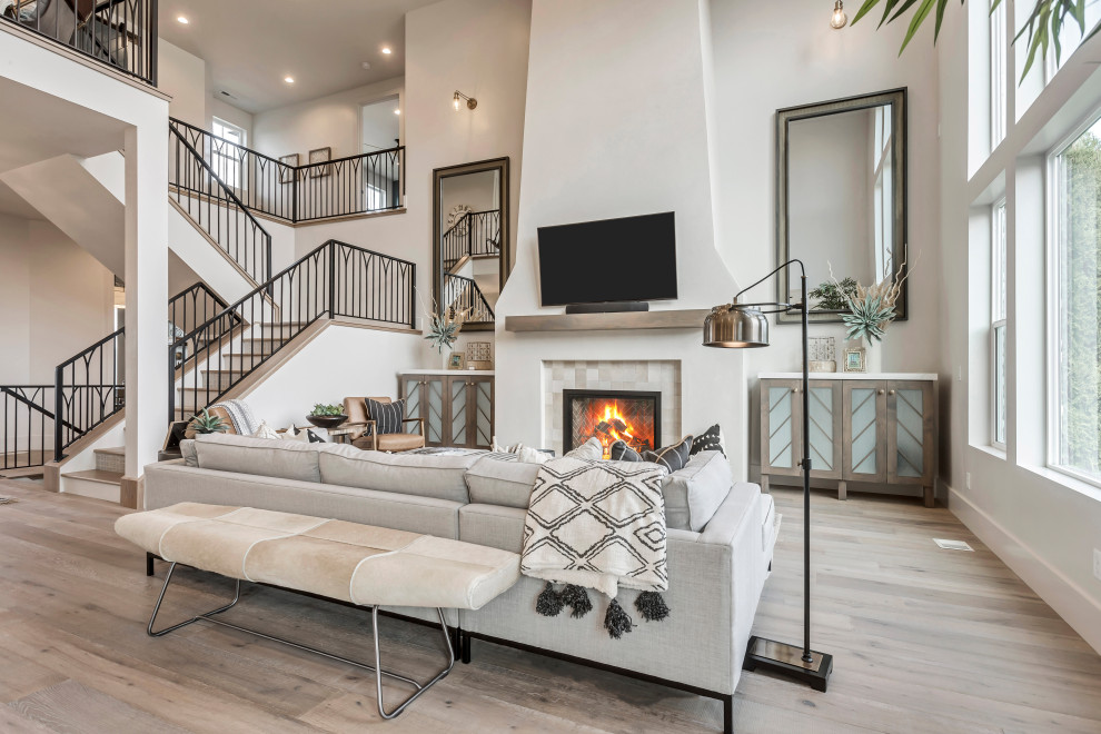 Design ideas for a transitional open concept living room in Salt Lake City with white walls, medium hardwood floors, a standard fireplace, a tile fireplace surround, a wall-mounted tv and brown floor.
