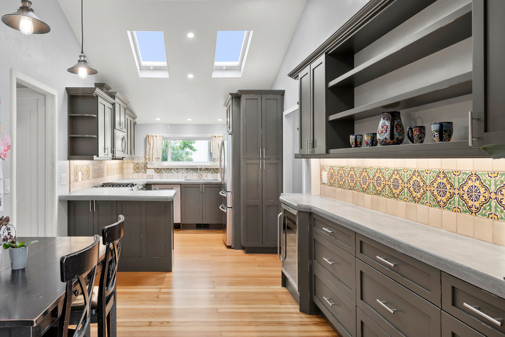 This is an example of a small traditional u-shaped kitchen in San Francisco with an undermount sink, shaker cabinets, distressed cabinets, concrete benchtops, ceramic splashback, stainless steel appliances, medium hardwood floors, brown floor and grey benchtop.