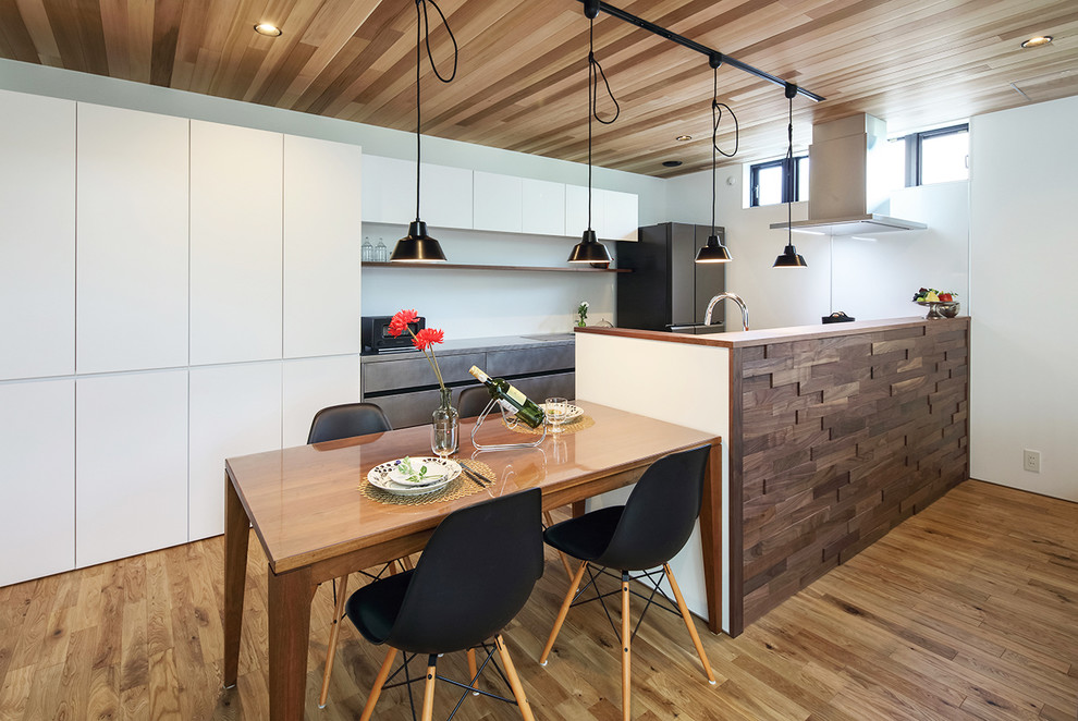 This is an example of a contemporary open plan kitchen in Other with medium hardwood floors and brown floor.