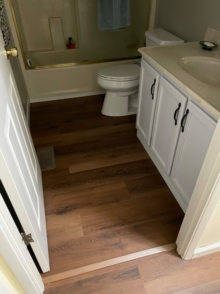 Design ideas for a medium sized classic bathroom in Sacramento with recessed-panel cabinets, white cabinets, an alcove bath, a shower/bath combination, a two-piece toilet, beige tiles, ceramic tiles, beige walls, wood-effect flooring, a built-in sink, brown floors, a sliding door, beige worktops, a single sink and a built in vanity unit.