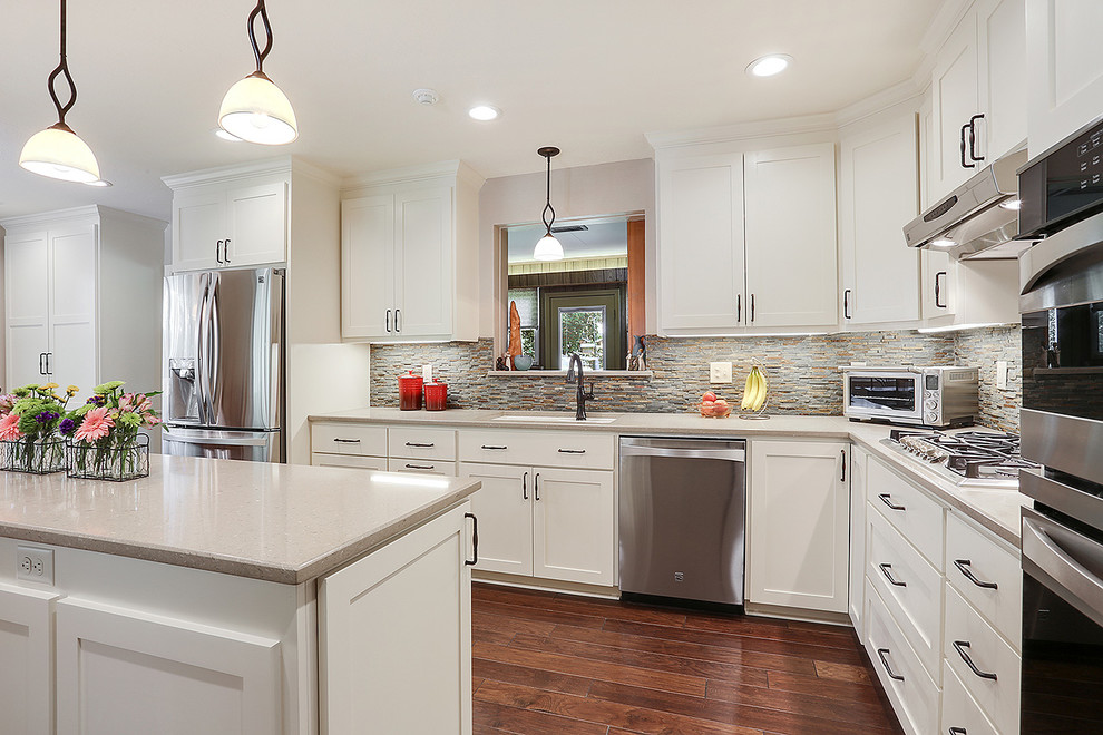 Inspiration for a transitional l-shaped kitchen in New Orleans with an undermount sink, shaker cabinets, white cabinets, brown splashback, stainless steel appliances, medium hardwood floors and with island.