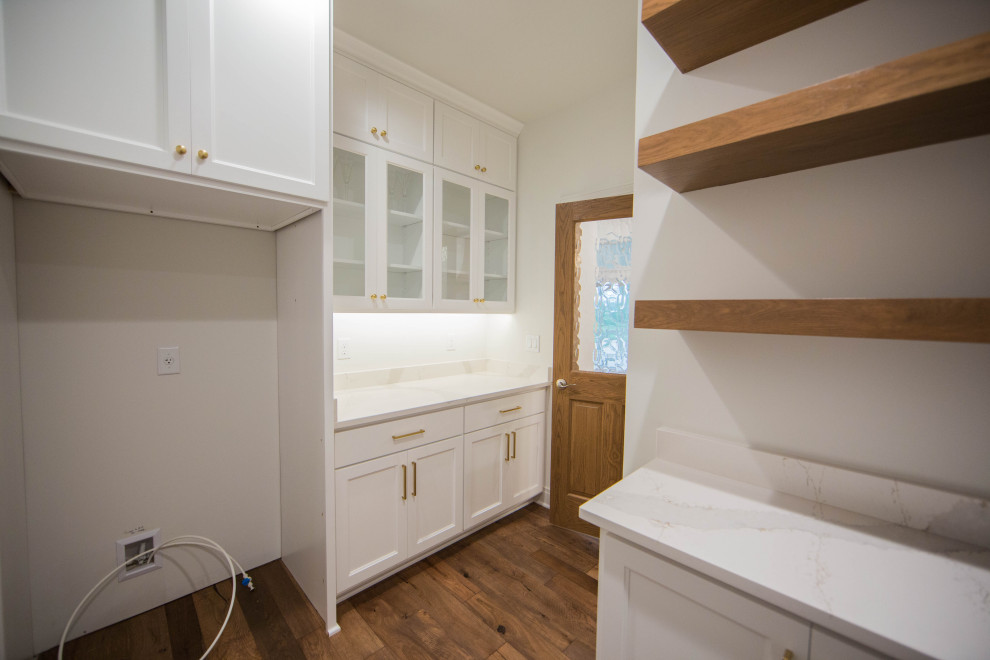Photo of an expansive traditional u-shaped kitchen pantry in Indianapolis with recessed-panel cabinets, white cabinets, marble worktops, white splashback, medium hardwood flooring, no island, brown floors and white worktops.