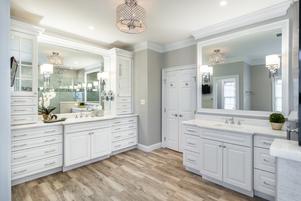 Photo of a large transitional master bathroom in DC Metro with raised-panel cabinets, white cabinets, a freestanding tub, a two-piece toilet, multi-coloured tile, porcelain tile, grey walls, porcelain floors, an undermount sink and marble benchtops.