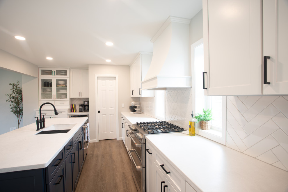 Inspiration for a large transitional vinyl floor kitchen remodel with shaker cabinets, white cabinets, quartz countertops, white backsplash, porcelain backsplash, stainless steel appliances, an island and white countertops