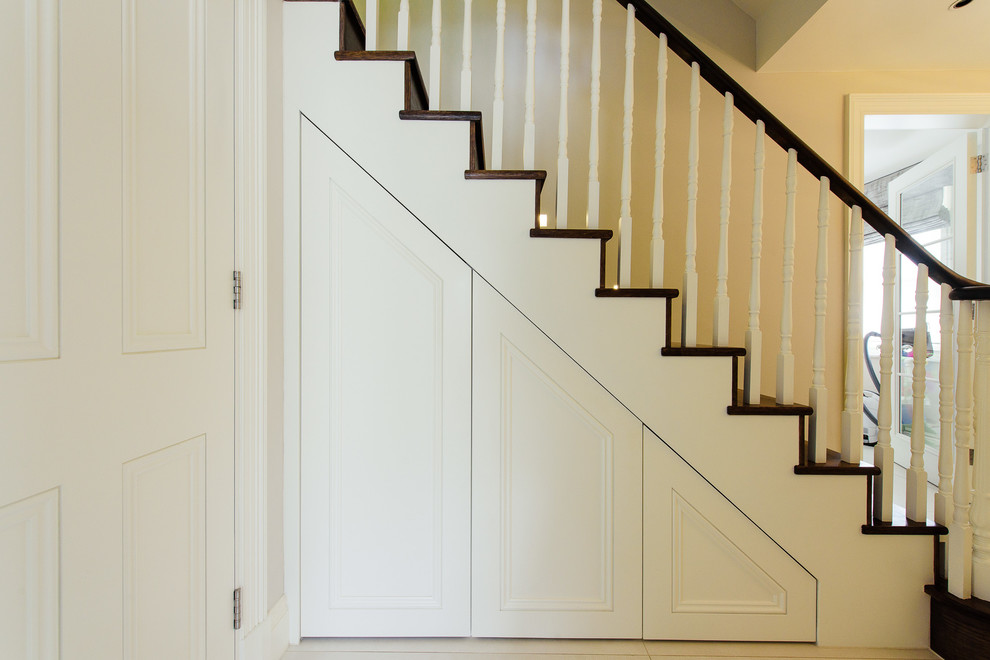 Photo of a large transitional wood straight staircase in London with wood risers.