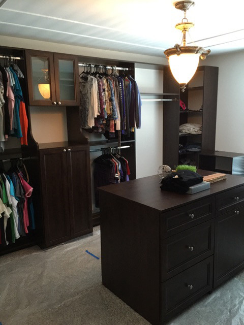 Photo of a large contemporary gender-neutral walk-in wardrobe in Newark with recessed-panel cabinets, dark wood cabinets and carpet.