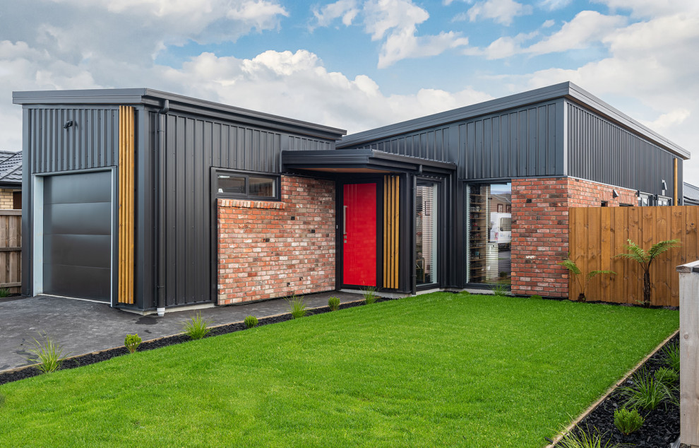 Photo of a small and black modern bungalow detached house in Christchurch with metal cladding, a butterfly roof, a metal roof and a black roof.