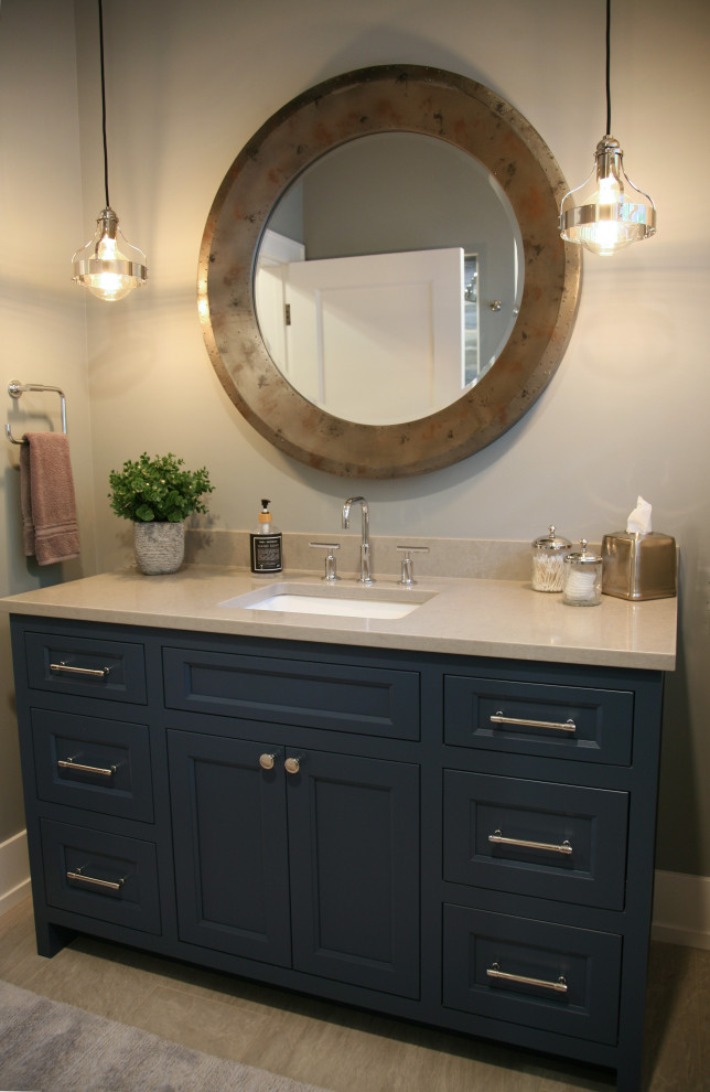 Inspiration for a mid-sized beach style bathroom in Milwaukee with shaker cabinets, white cabinets, a one-piece toilet, white tile, beige walls, porcelain floors, an undermount sink, engineered quartz benchtops, grey floor, a hinged shower door, white benchtops, a single vanity and a built-in vanity.