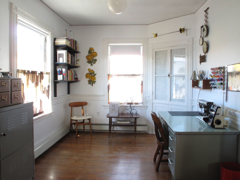 Eclectic craft room in Boston with white walls, dark hardwood floors and a freestanding desk.