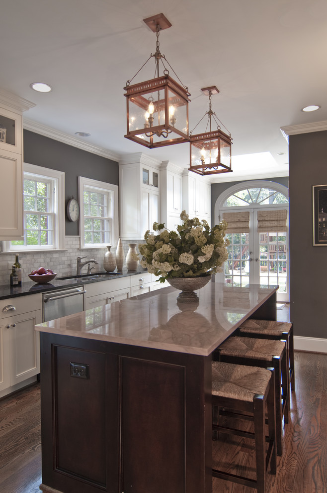 Elegant kitchen photo in Charlotte with white backsplash, stone tile backsplash, white cabinets, recessed-panel cabinets and a double-bowl sink