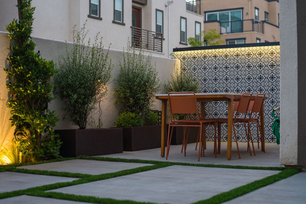 Kleiner Moderner Garten im Frühling, hinter dem Haus mit Hochbeet, direkter Sonneneinstrahlung, Betonboden und Steinzaun in Los Angeles
