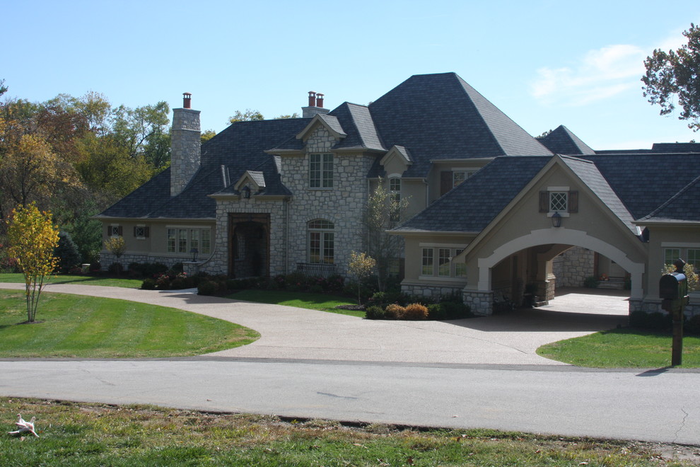 This is an example of an expansive country two-storey beige exterior in St Louis with stone veneer.