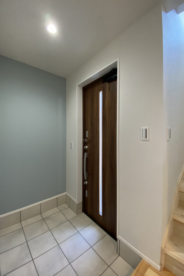 Ejemplo de entrada blanca con paredes azules, puerta simple, puerta de madera oscura, papel pintado y papel pintado