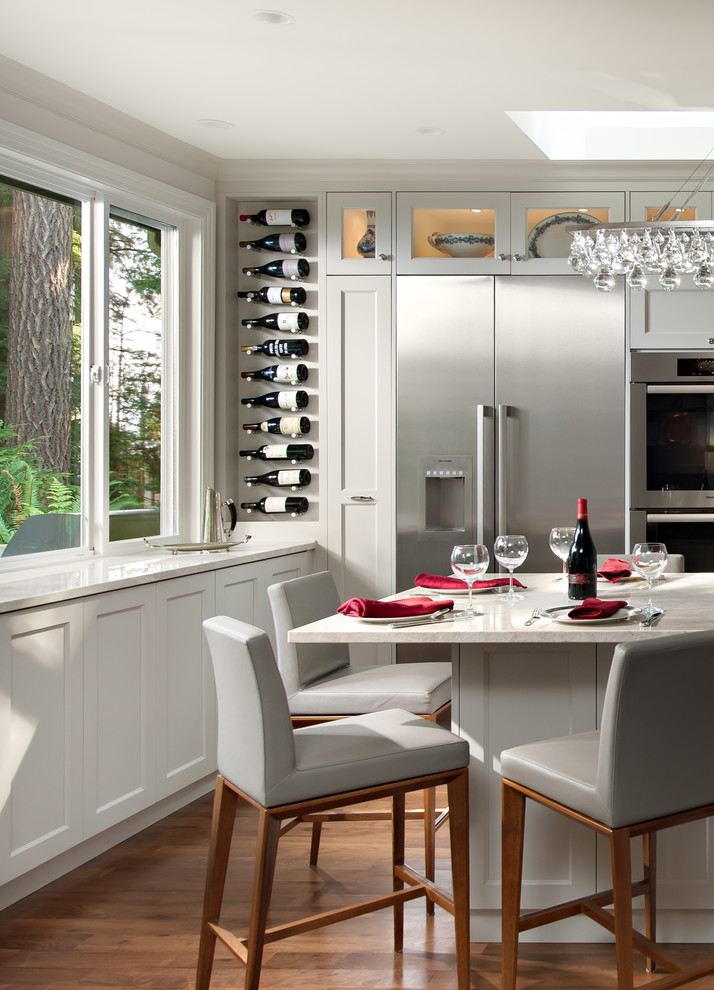 Example of a mid-sized transitional l-shaped medium tone wood floor and brown floor eat-in kitchen design in Vancouver with recessed-panel cabinets, gray cabinets, wood countertops, stainless steel appliances, an island and beige countertops