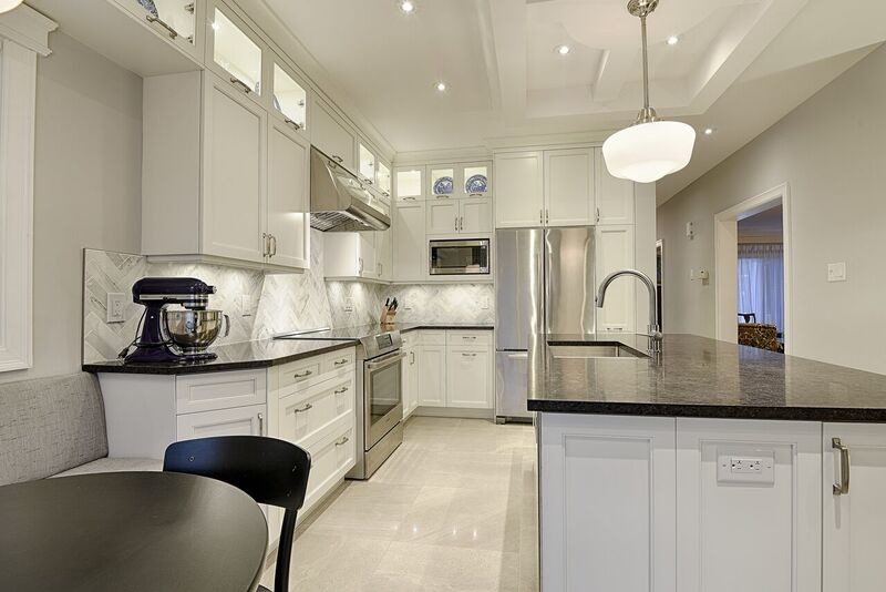 Inspiration for a large transitional l-shaped ceramic tile eat-in kitchen remodel in Ottawa with an undermount sink, recessed-panel cabinets, white cabinets, granite countertops, white backsplash, stone tile backsplash, stainless steel appliances and an island