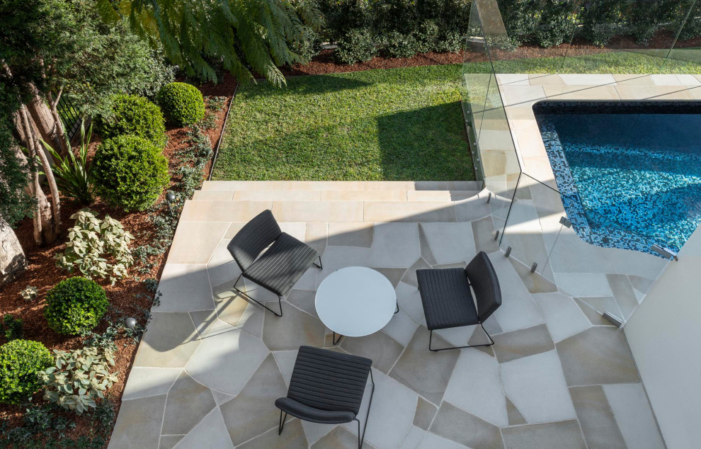 Réalisation d'un petit piscine avec aménagement paysager arrière design avec des pavés en pierre naturelle.