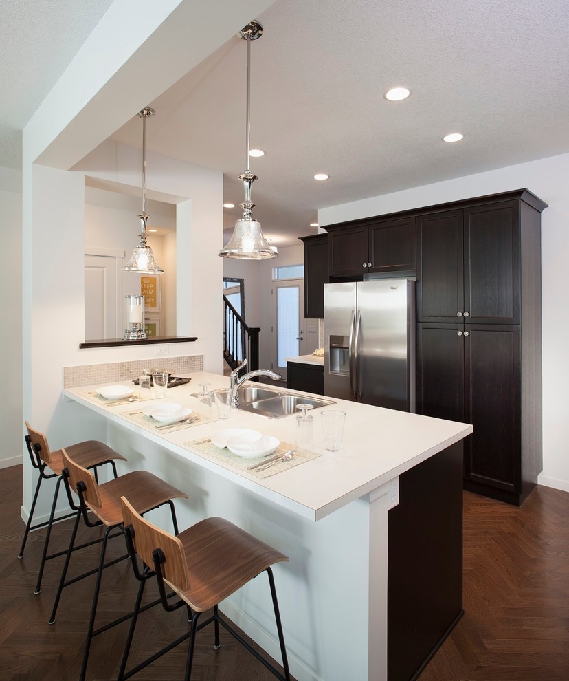 Photo of a contemporary kitchen in Edmonton with a double-bowl sink, shaker cabinets, dark wood cabinets and stainless steel appliances.