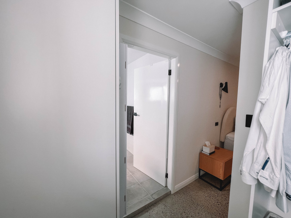 Mittelgroßer, Neutraler Skandinavischer Begehbarer Kleiderschrank mit flächenbündigen Schrankfronten, weißen Schränken, Betonboden, grauem Boden und Holzdecke in Sydney