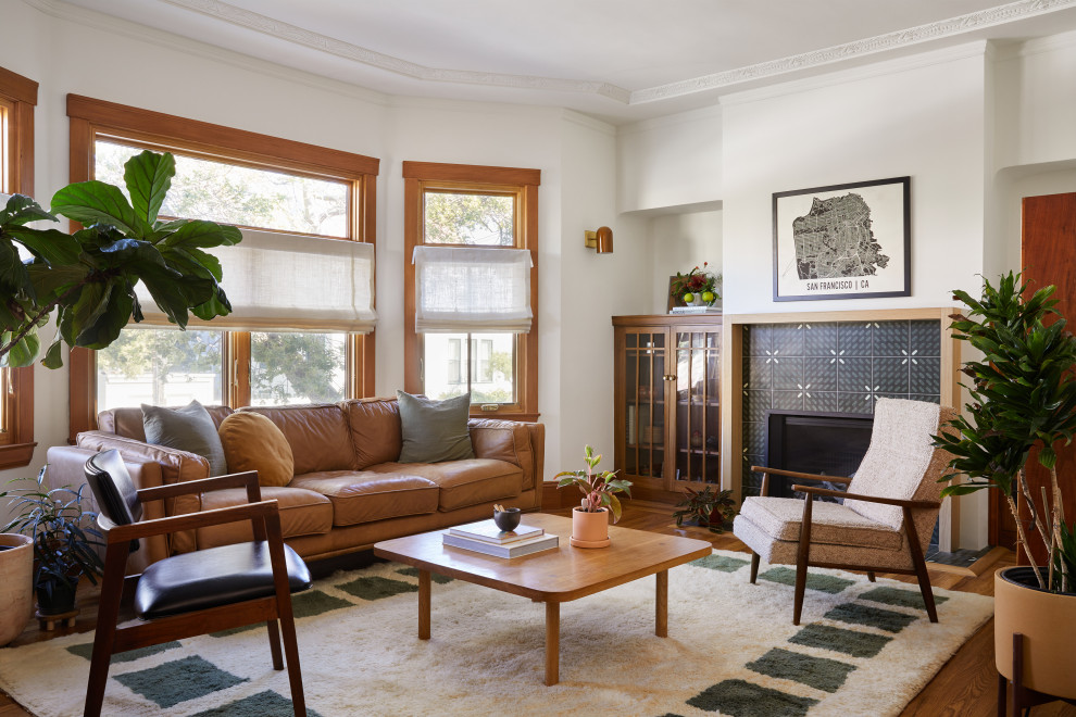 This is an example of a small victorian enclosed living room in San Francisco with white walls, medium hardwood flooring, a standard fireplace, a tiled fireplace surround, a freestanding tv, brown floors and a coffered ceiling.