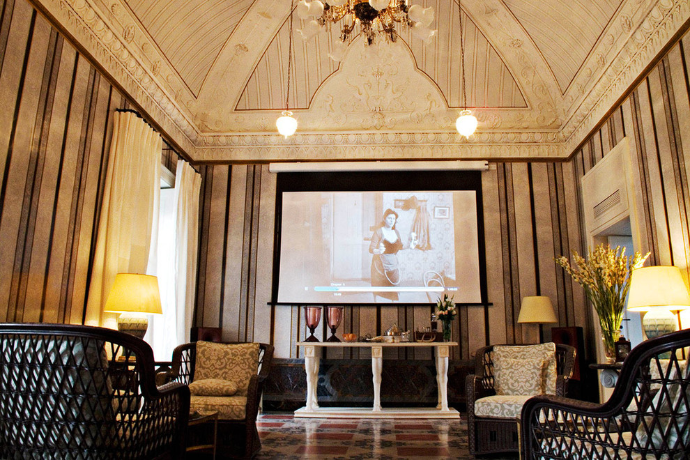 Photo of a large traditional enclosed home theatre in New York with multi-coloured walls, terra-cotta floors and a projector screen.