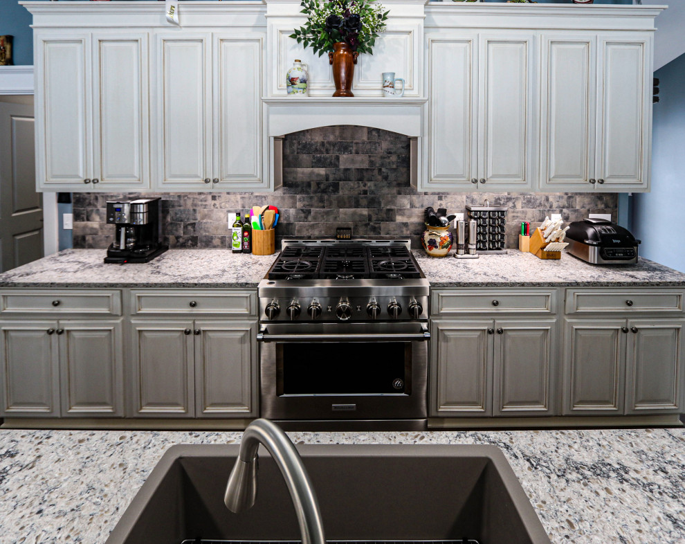 Bild på ett mellanstort vintage beige beige kök, med en undermonterad diskho, luckor med upphöjd panel, vita skåp, bänkskiva i kvarts, grått stänkskydd, stänkskydd i keramik, rostfria vitvaror, mellanmörkt trägolv, en köksö och brunt golv