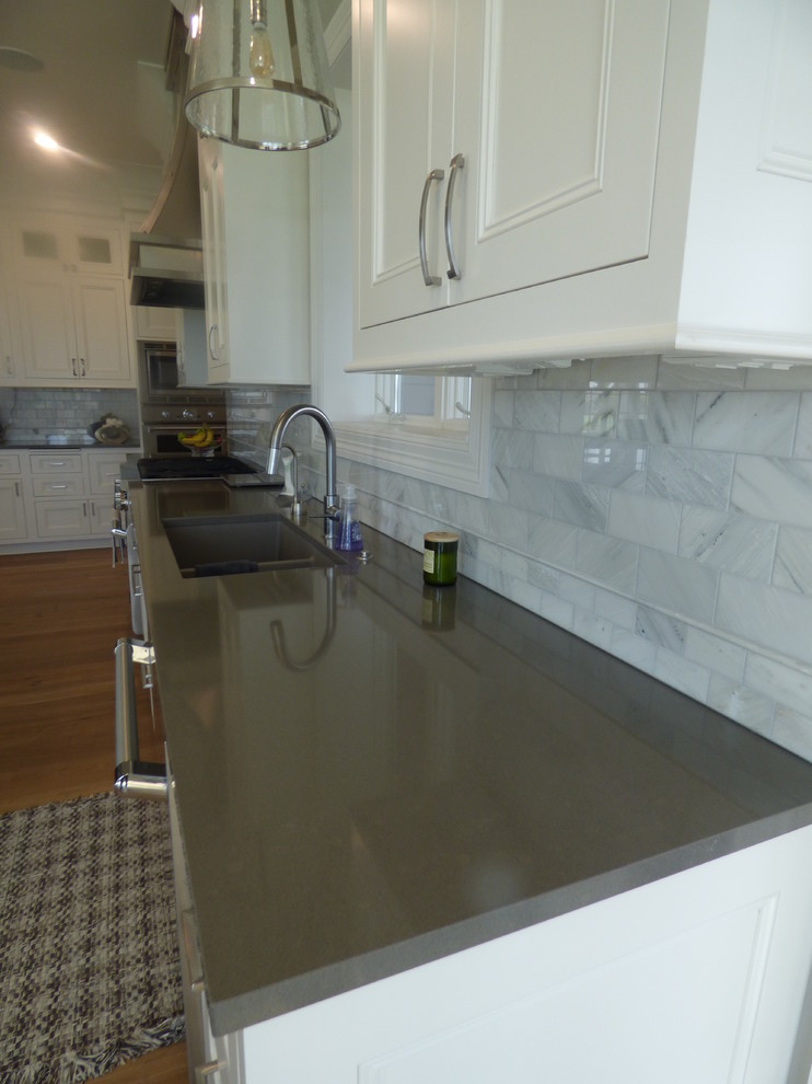Eat-in kitchen - large transitional l-shaped light wood floor eat-in kitchen idea with an undermount sink, recessed-panel cabinets, white cabinets, quartz countertops, white backsplash, subway tile backsplash, stainless steel appliances and an island