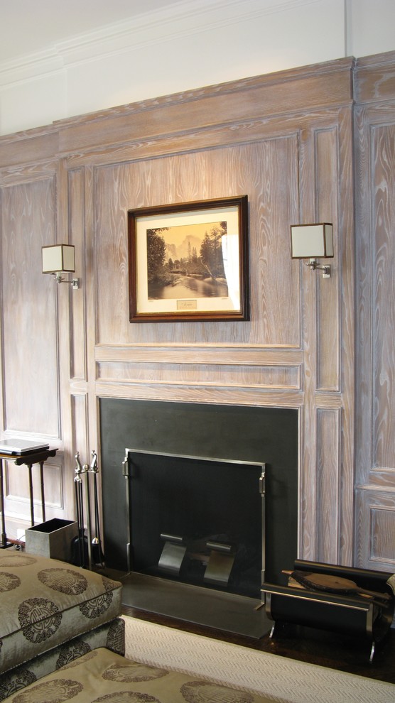 Photo of a mid-sized traditional enclosed family room in New York with a library, grey walls, dark hardwood floors, a standard fireplace, a stone fireplace surround, a built-in media wall and brown floor.
