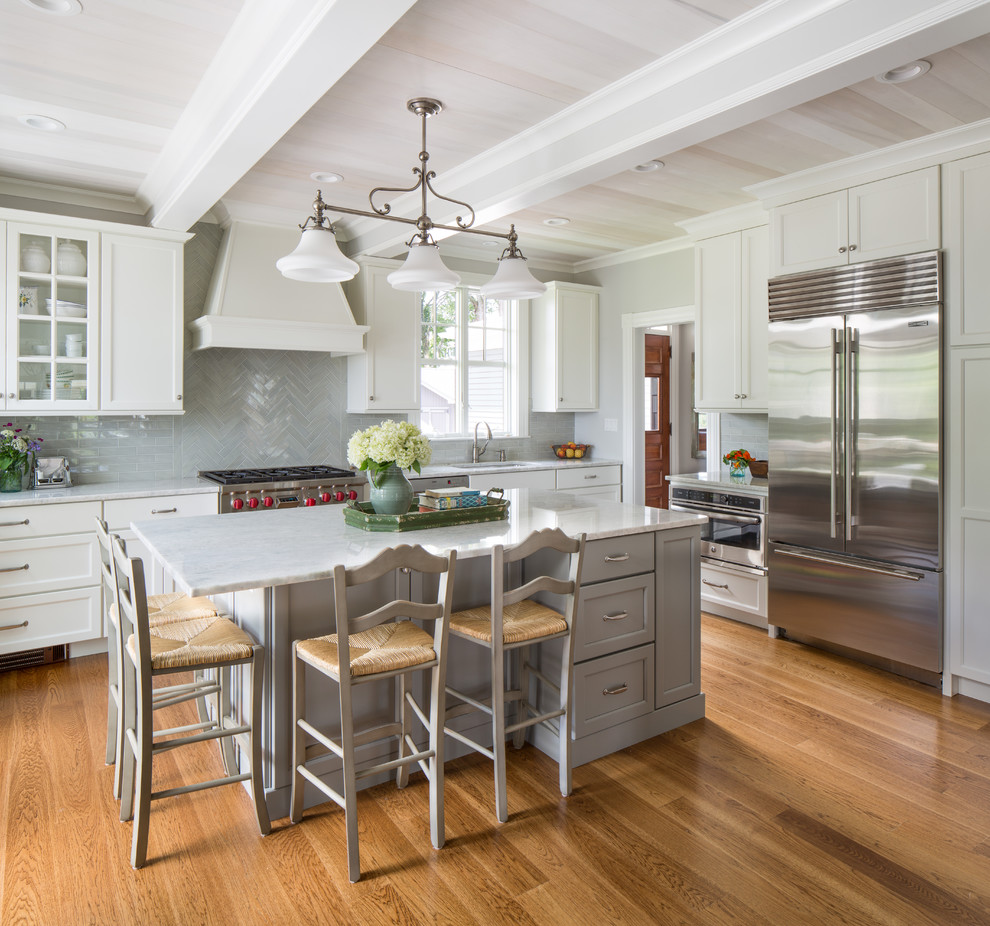 Photo of a traditional kitchen in Other with recessed-panel cabinets, white cabinets, grey splashback, stainless steel appliances, medium hardwood floors, with island and brown floor.