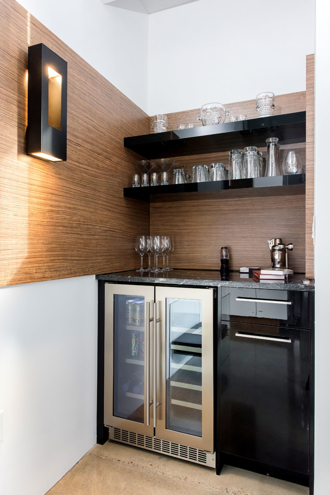 This is an example of a small modern single-wall home bar in Other with no sink, flat-panel cabinets, black cabinets, granite benchtops, brown splashback and concrete floors.