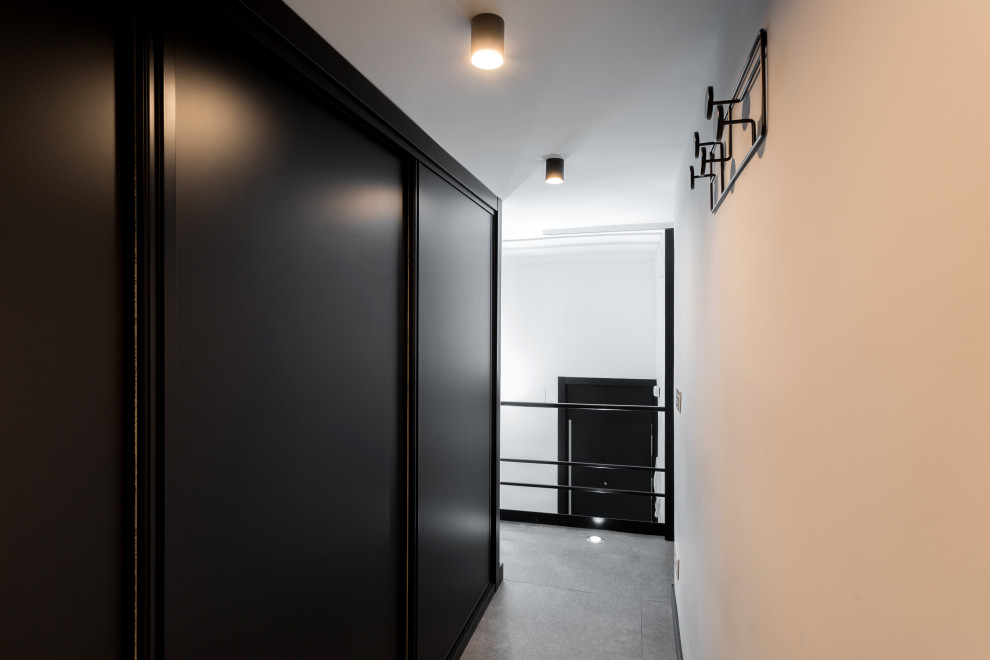 На фото: маленькая гардеробная комната унисекс в стиле лофт с черными фасадами, полом из керамогранита и серым полом для на участке и в саду с