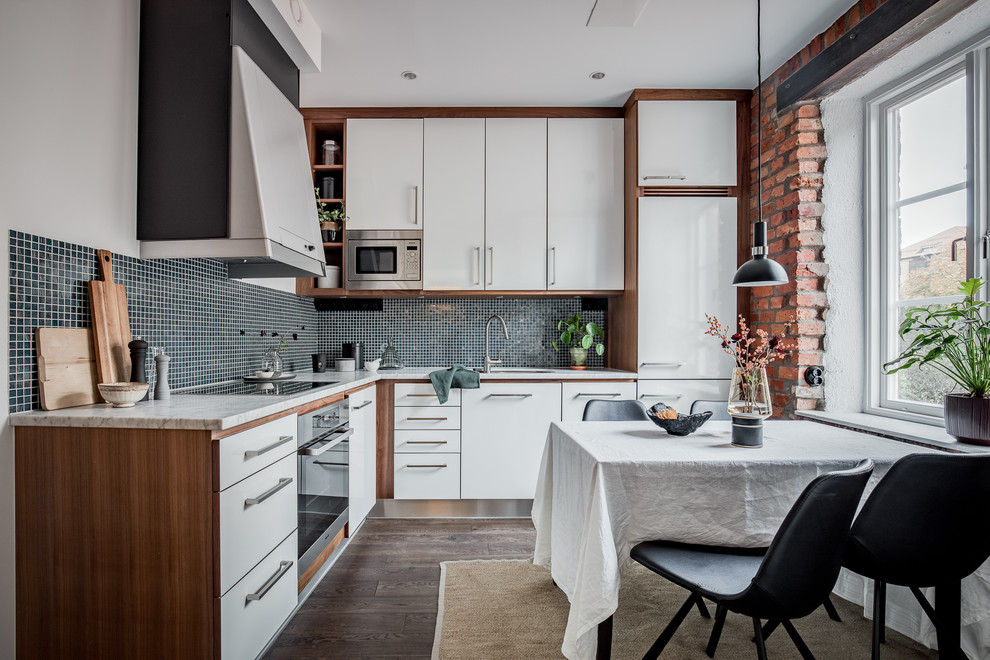 This is an example of a scandinavian l-shaped eat-in kitchen in Gothenburg with an undermount sink, flat-panel cabinets, white cabinets, blue splashback, mosaic tile splashback, panelled appliances, dark hardwood floors, no island and brown floor.