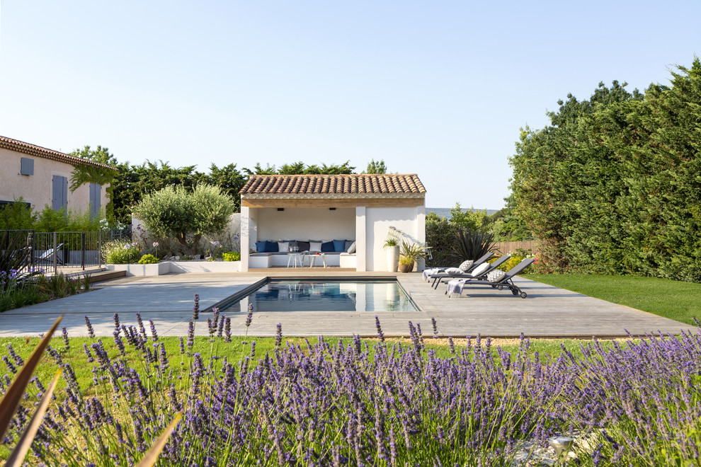Photo of a mid-sized mediterranean backyard rectangular lap pool in Marseille with a pool house and decking.