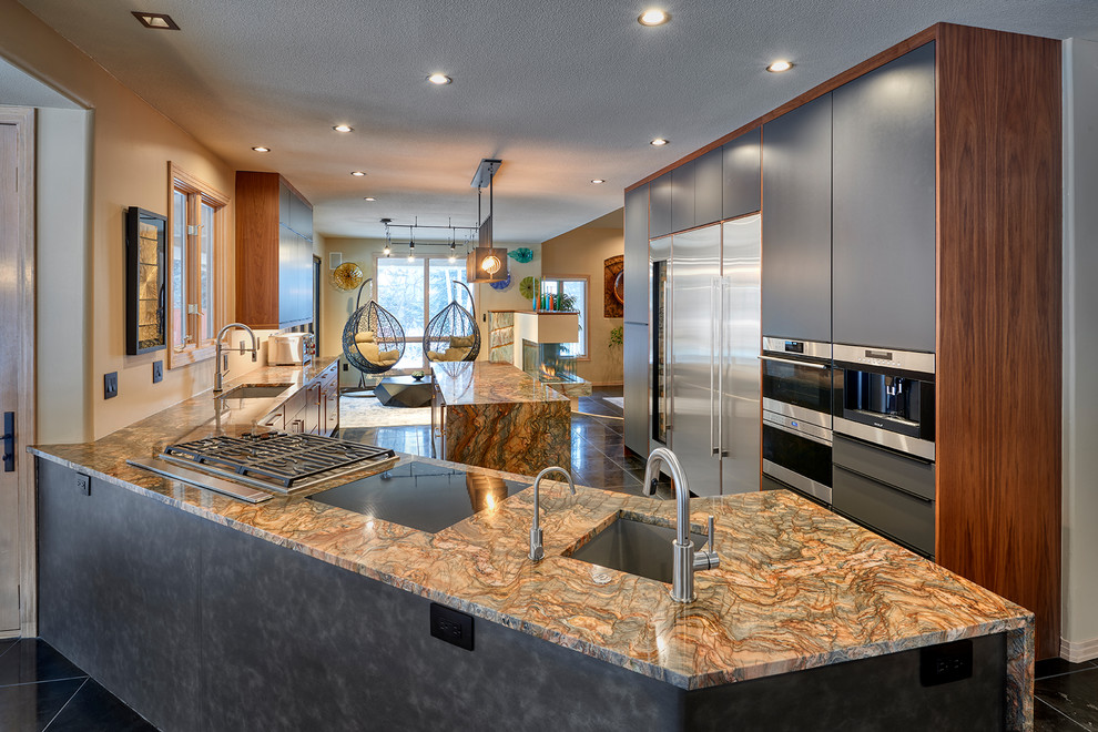 This is an example of a mid-sized eclectic eat-in kitchen in Denver with an undermount sink, flat-panel cabinets, granite benchtops, stainless steel appliances, with island, black floor and multi-coloured benchtop.